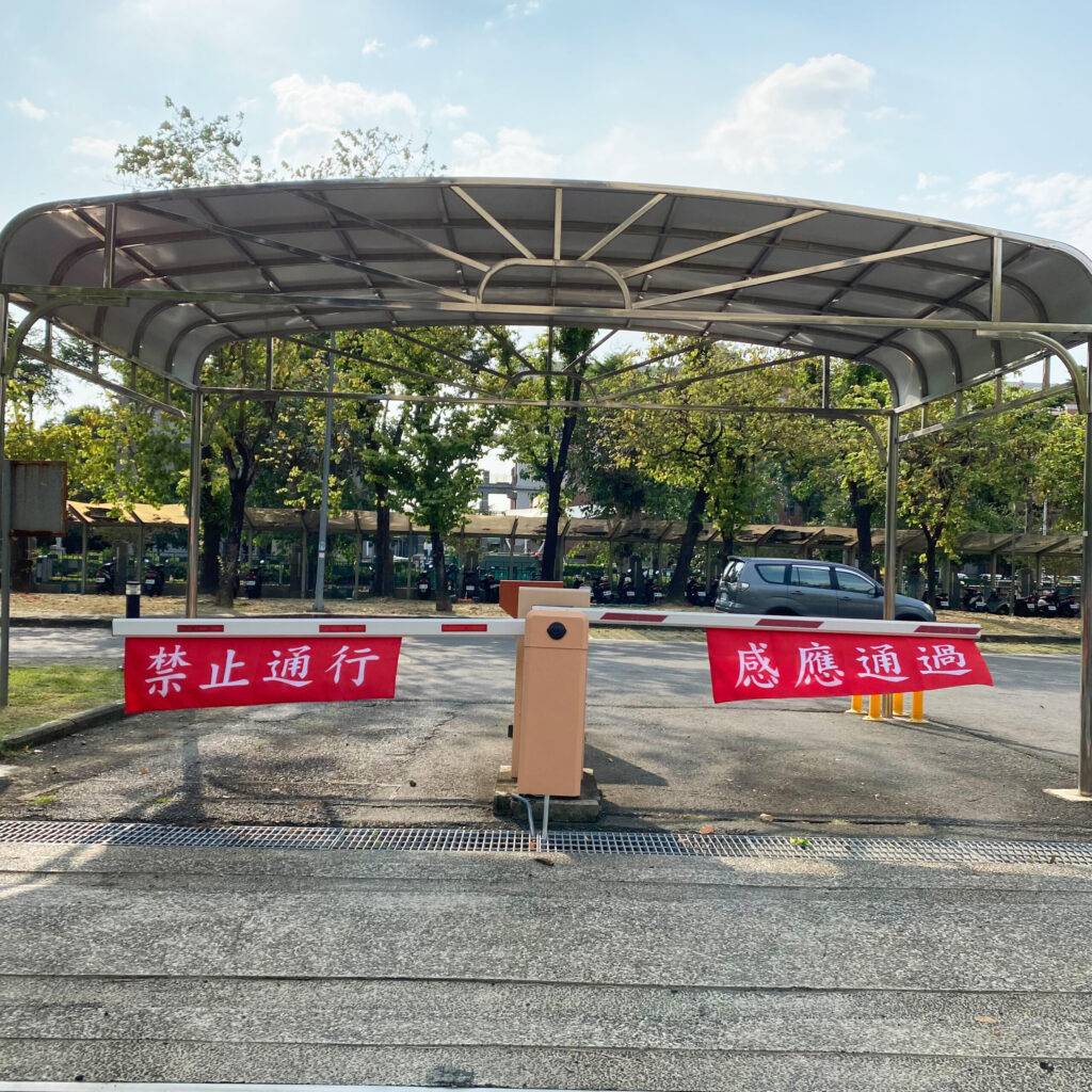 兩面布條並且固定在停車場車的柵欄上面、右邊那面印感應通過，左邊那面印禁止通行