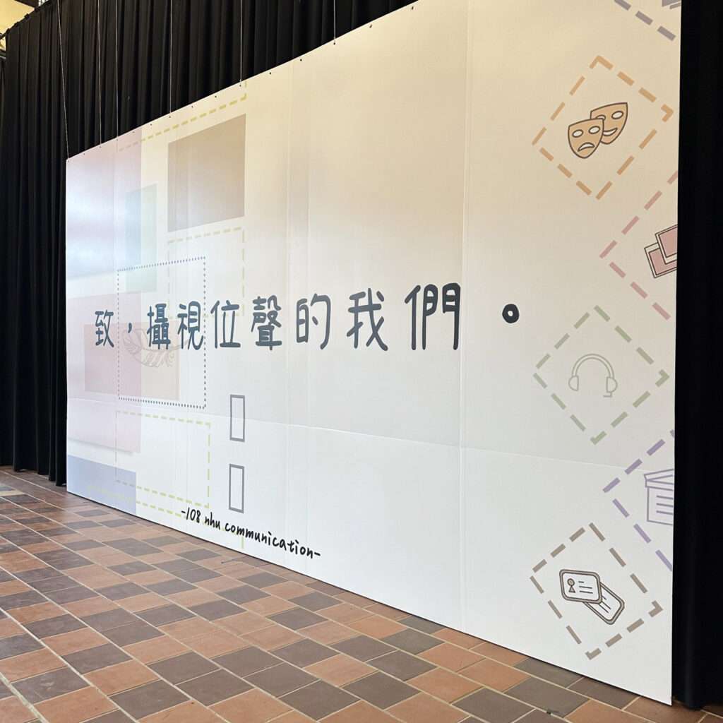 一面大圖輸出，懸掛在布幕前方。上面有致攝視位聲的我們字樣(右側視角)