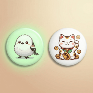 銀喉長尾山雀與招財貓圖案徽章，展示夜光材質在不同色調下的顯色效果，色彩飽滿細緻。