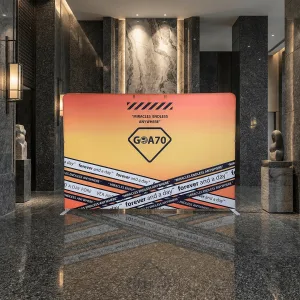 安麗GOA70主題視覺背板，飯店大廳走廊搭建實景，橘黃漸層主視覺搭配黑色英文標語飾條設計