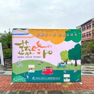 佛光山蔬咚po戶外市集快幕秀展架，校園戶外廣場搭建實景，搭配木製矮舞台展示活動主視覺