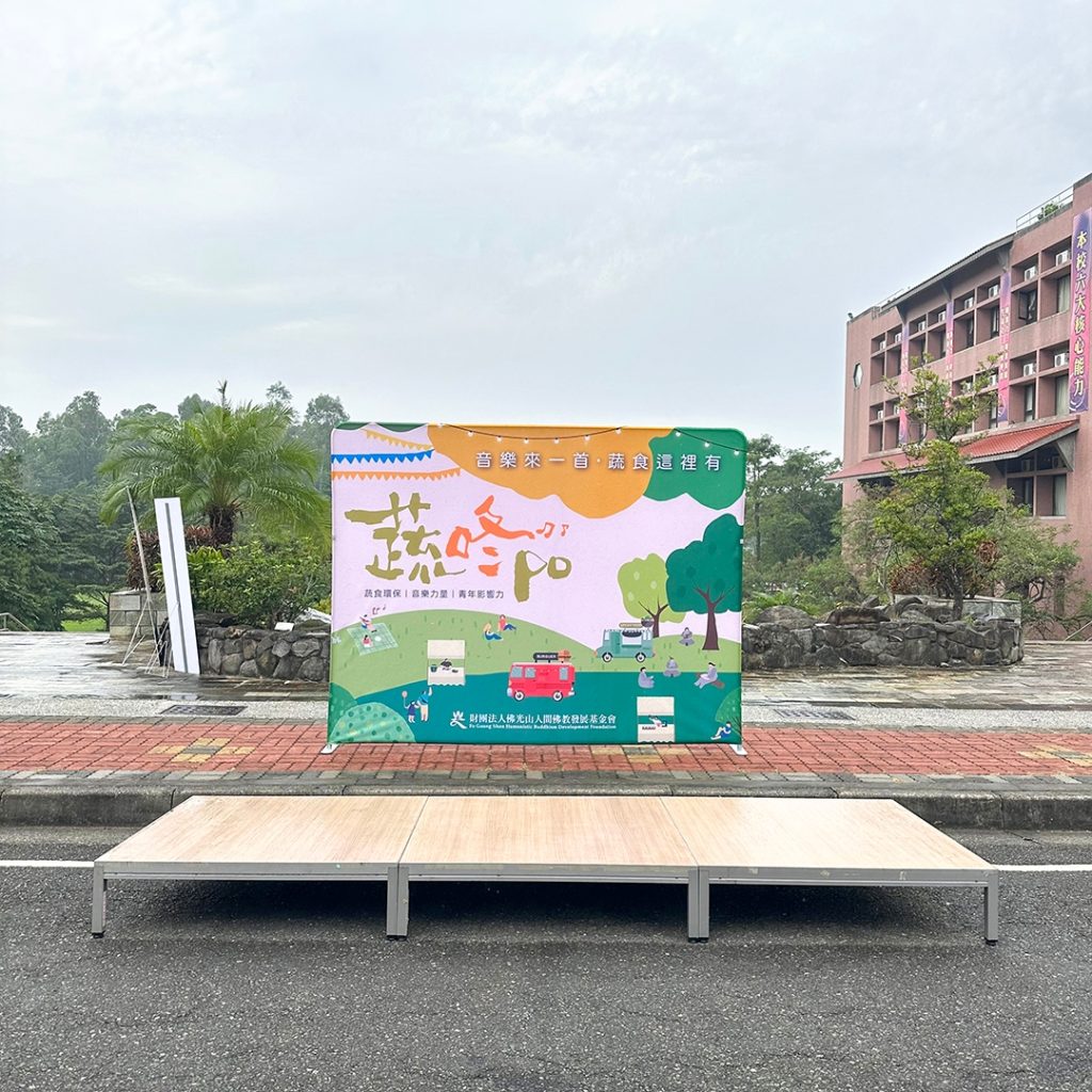 佛光山蔬咚po戶外市集快幕秀展架，蔬食環保與音樂力量活動背板，粉嫩色調插畫風格設計與周邊環境全景